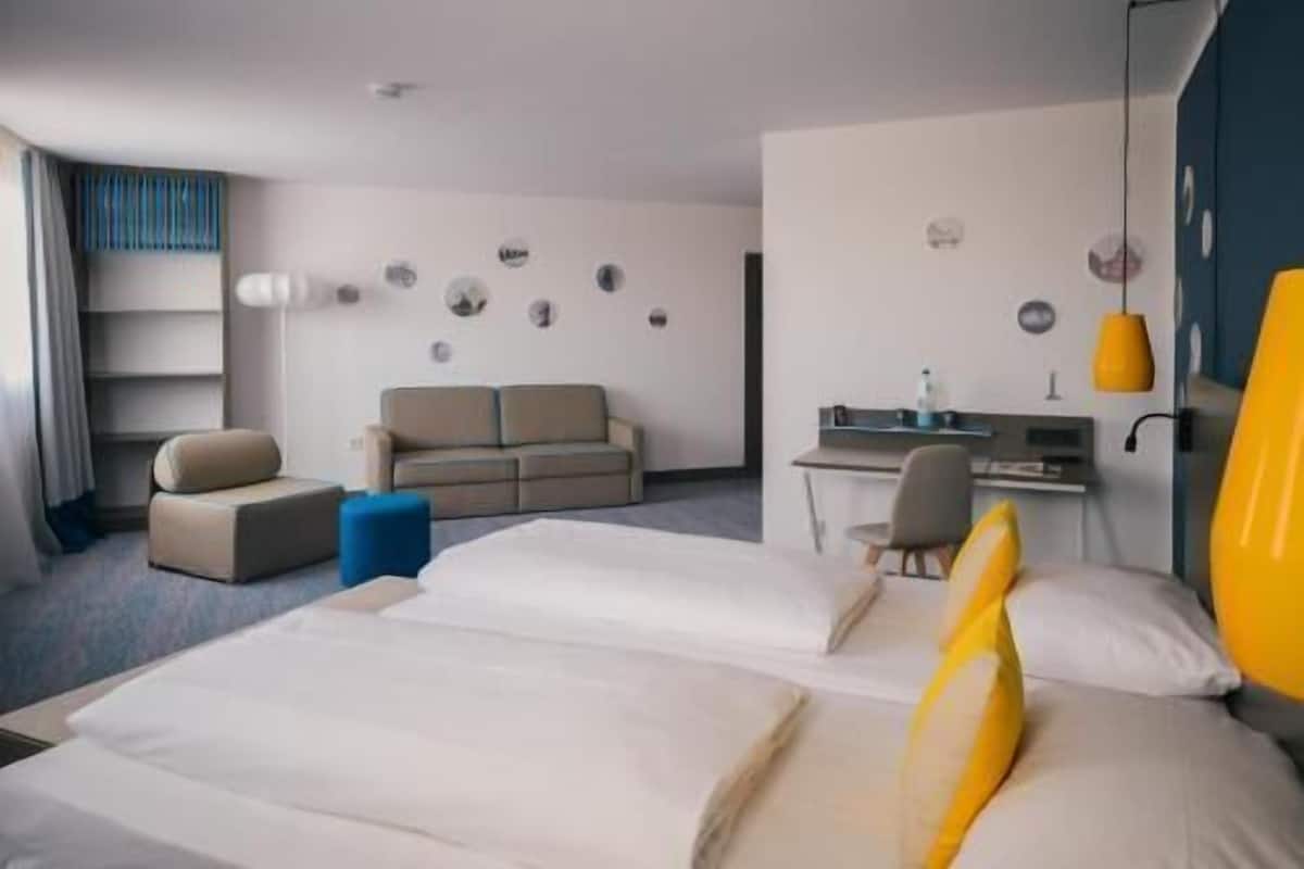 A hotel room with two beds, a sofa, a desk, and a chair.