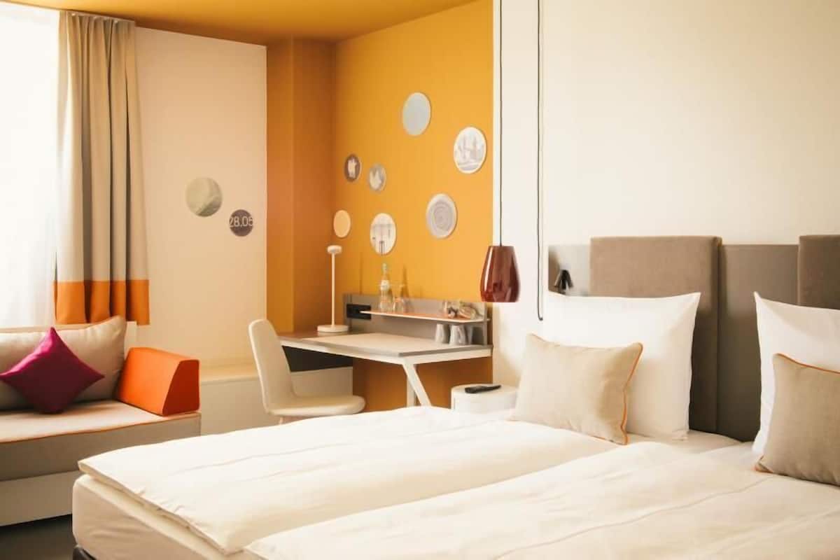 A hotel room with a bed, a desk, a chair, and a sofa.