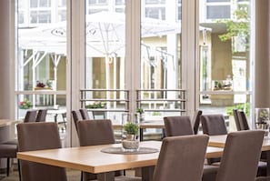 Un restaurante con un amplio ventanal, varias mesas y sillas.