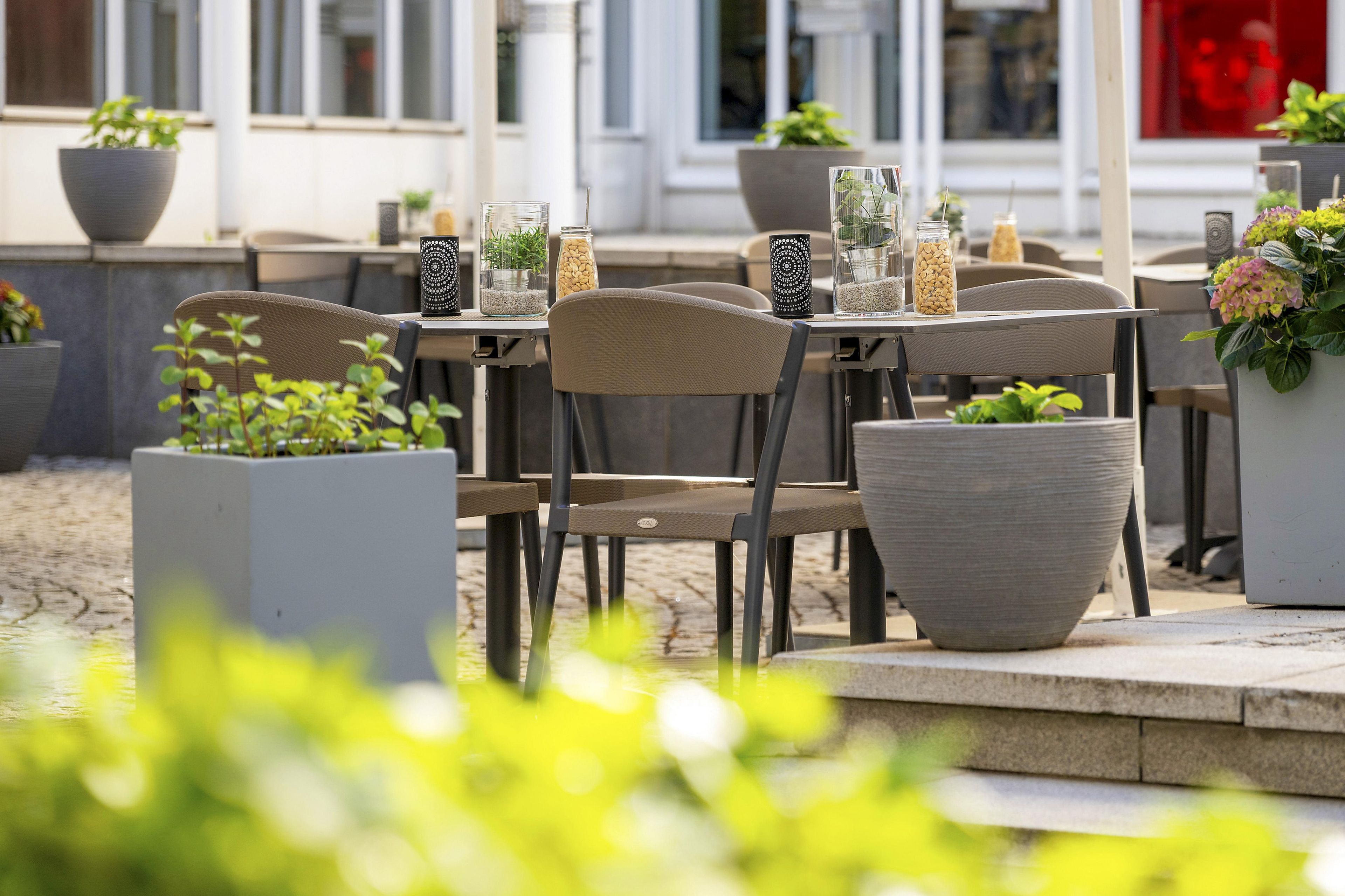 An outdoor seating area with tables and chairs, potted plants, and decorative items.