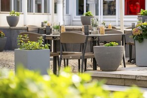 An outdoor seating area with tables and chairs, potted plants, and decorative items.