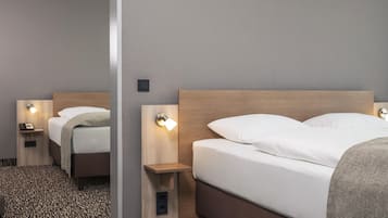 A hotel room with a bed, bedside tables, and wall-mounted lamps.