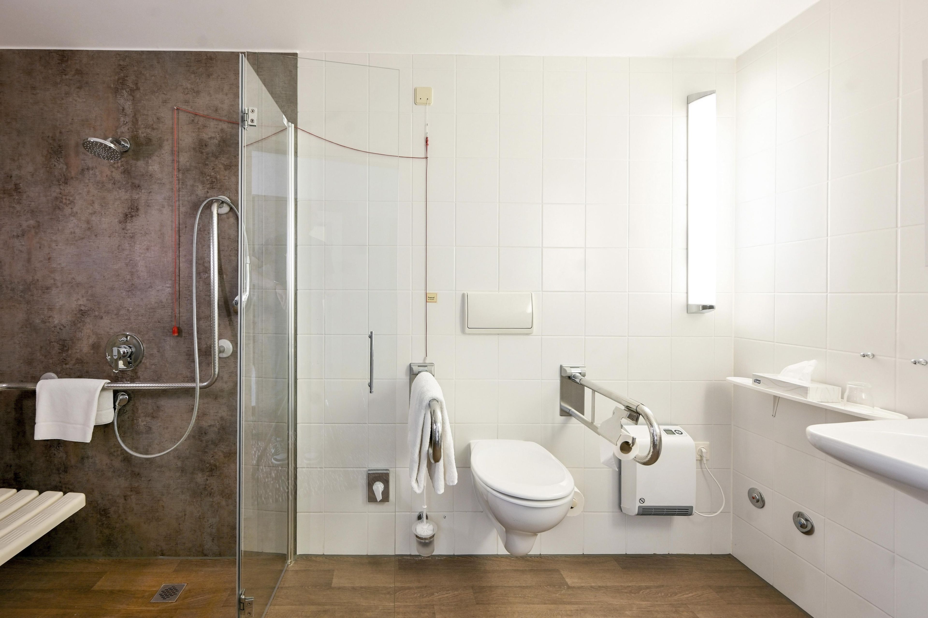 Ein modernes Badezimmer mit einer gläsernen Dusche, Toilette, Bidet und Waschbecken.