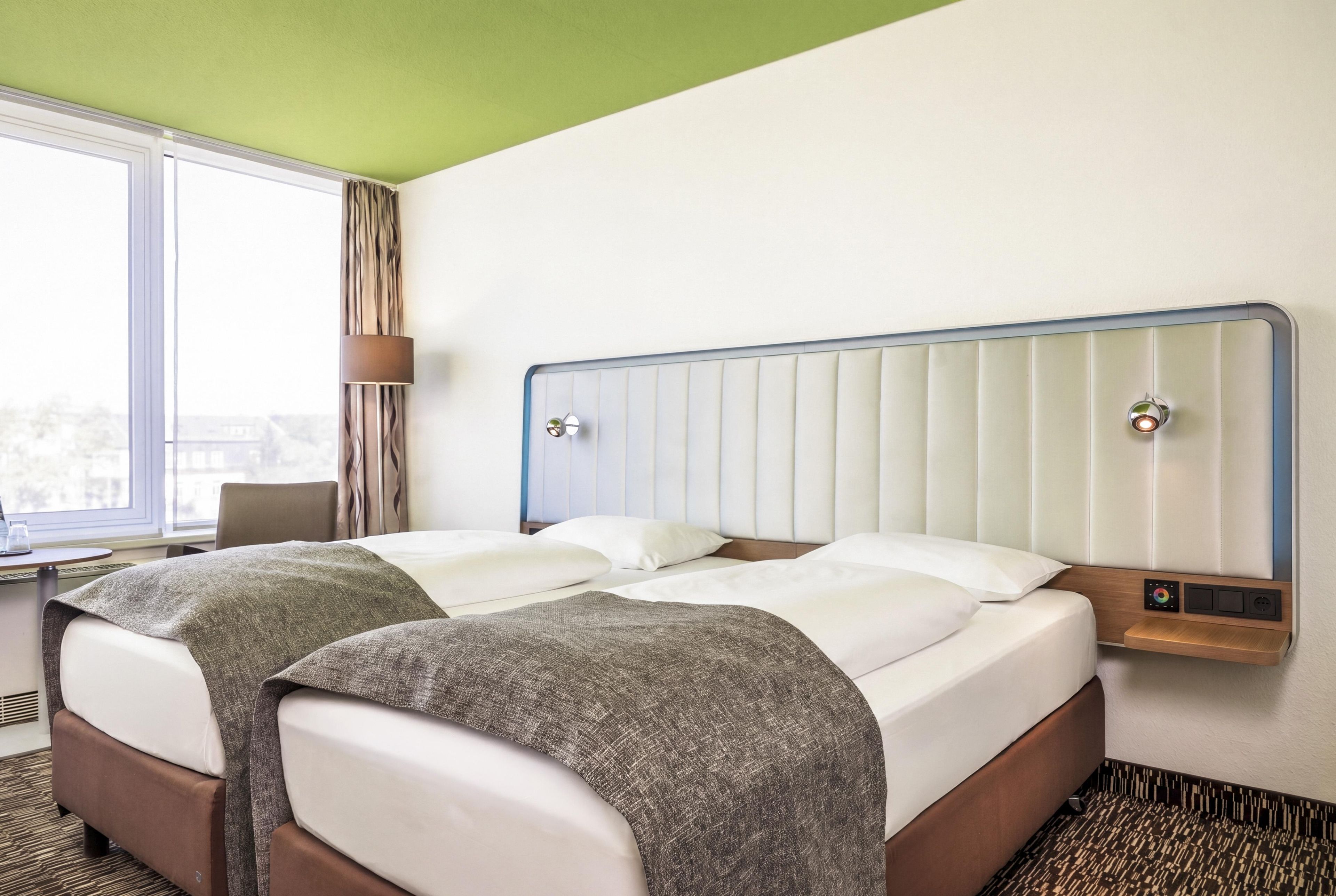 A hotel room with a bed, a desk, and a window.