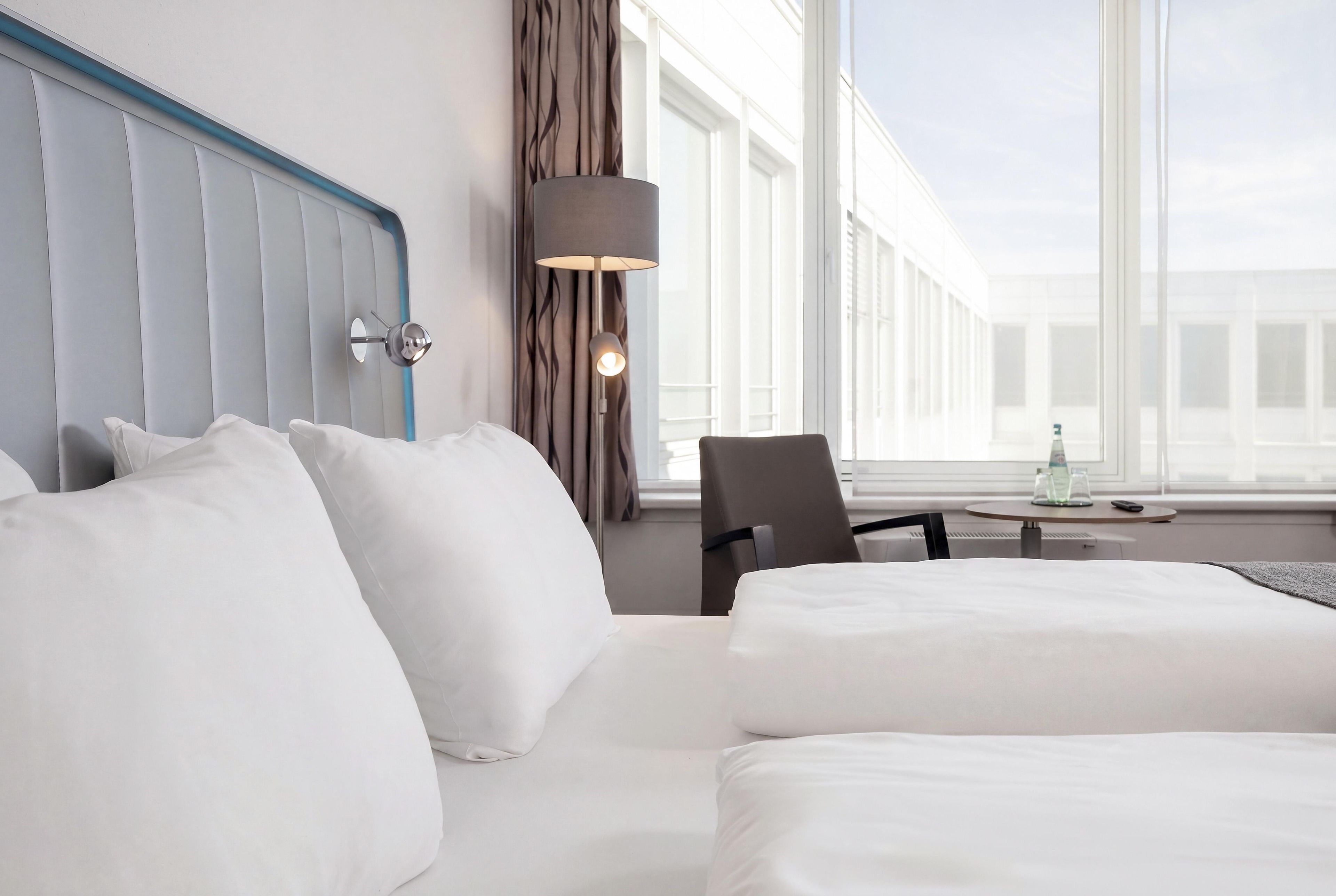 Ein Hotelzimmer mit einem großen Bett, einem Sessel, einem Tisch und einer Lampe.