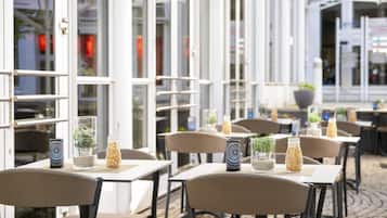Ein Straßencafé mit Tischen und Stühlen, einige mit Pflanzen und Dekoration.