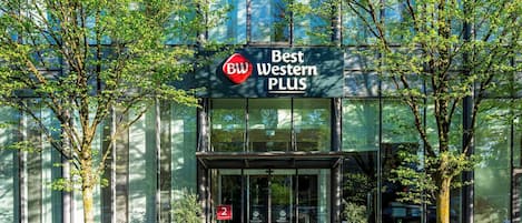 Ein modernes Gebäude mit Glasfassade, einem Schild mit der Aufschrift 'Best Western PLUS' und einem roten Teppich, der zum Eingang führt.
