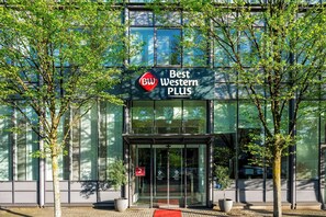 Een modern gebouw met een glazen gevel, een bord waarop 'Best Western PLUS' staat en een rode loper die naar de ingang leidt.