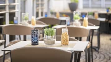 A cafe with tables and chairs, some with drinks and plants.