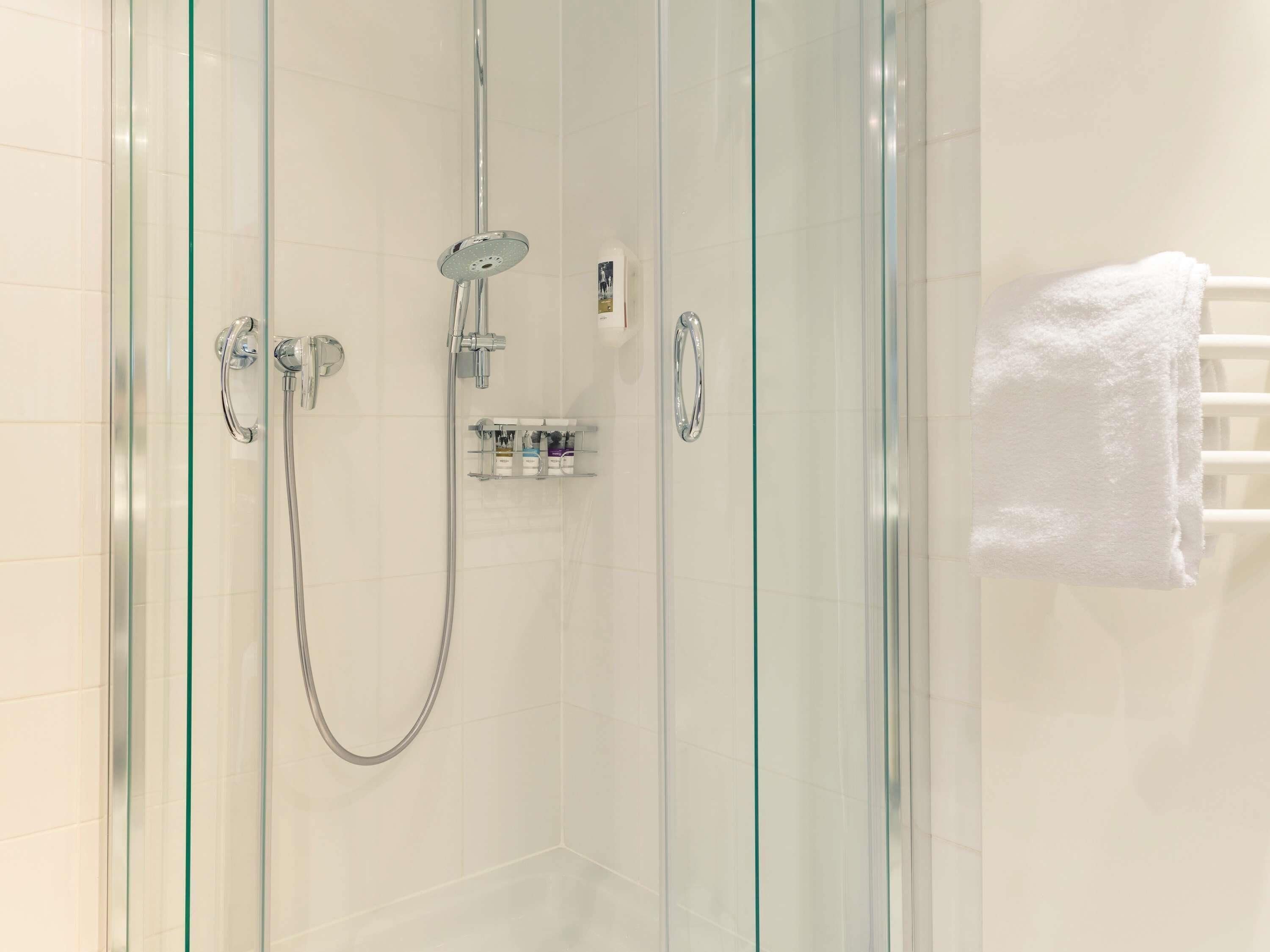 Ducha envuelta en vidrio con cabezal de ducha de mano y grifo empotrado.