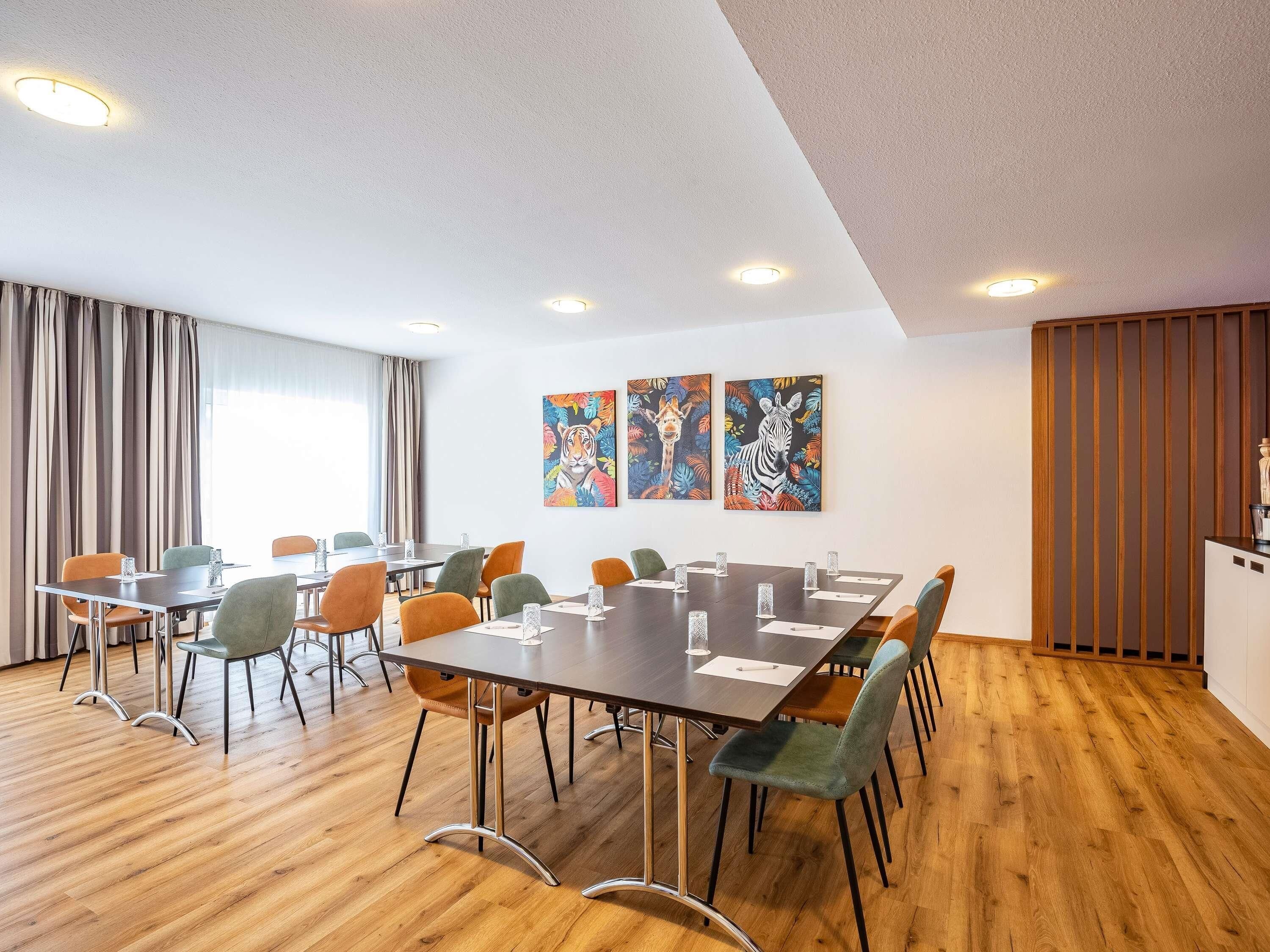 Un salón de conferencias con pisos de madera, sillas modernas y una gran mesa.