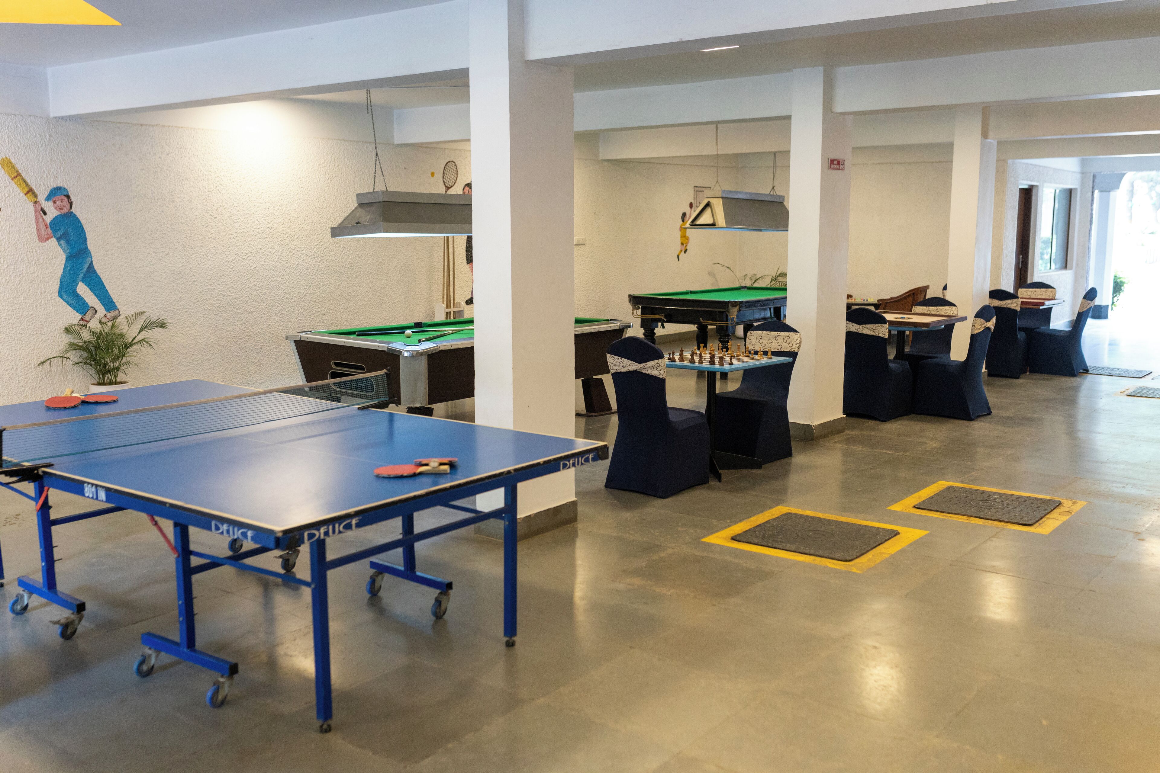 A spacious indoor area with a ping pong table, a pool table, and a foosball table.