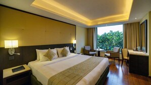 Habitación de hotel con una cama grande, un escritorio y vistas a zonas verdes.