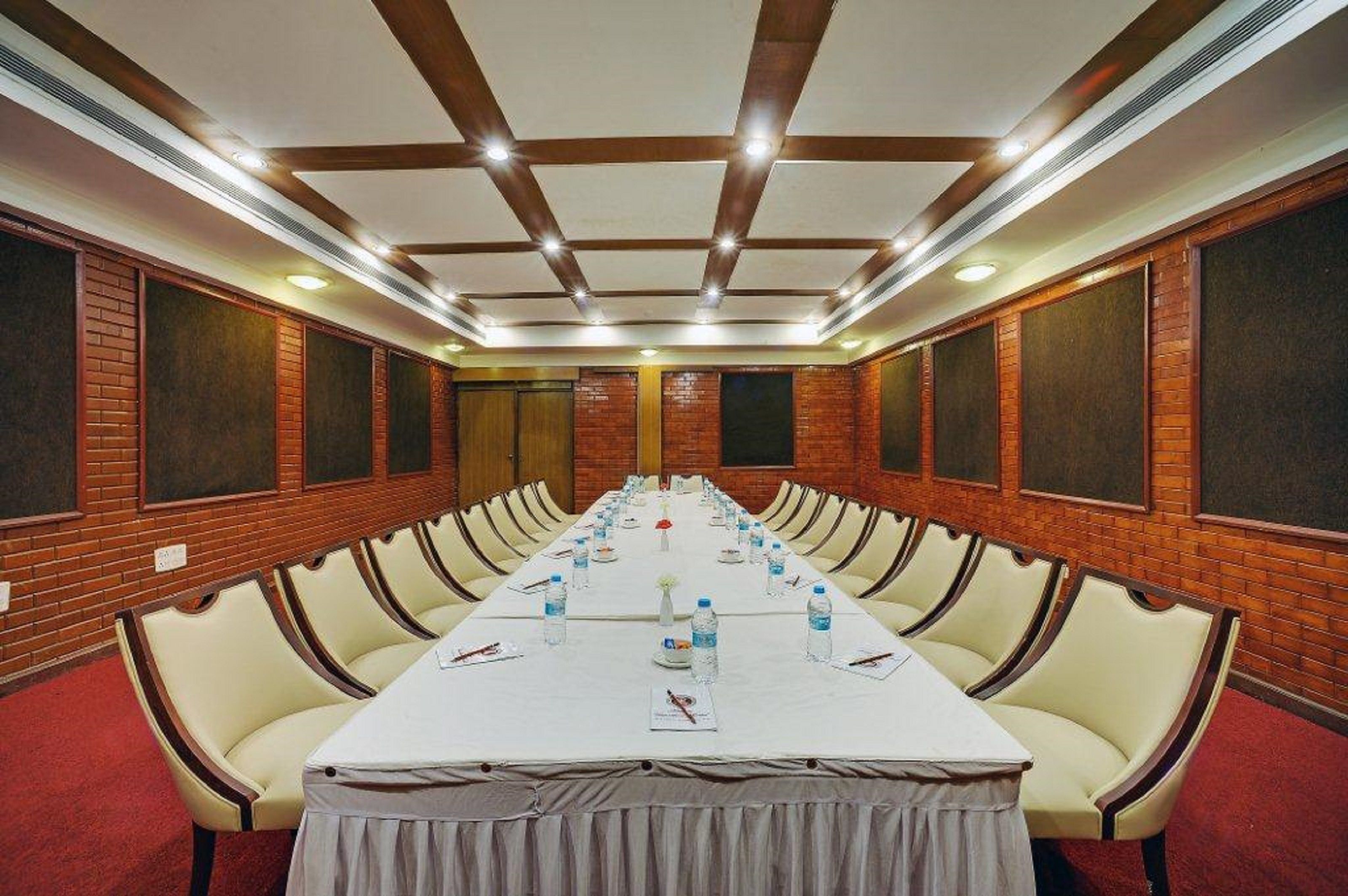 Une salle de conférence avec une longue table, des chaises et un mur en briques.
