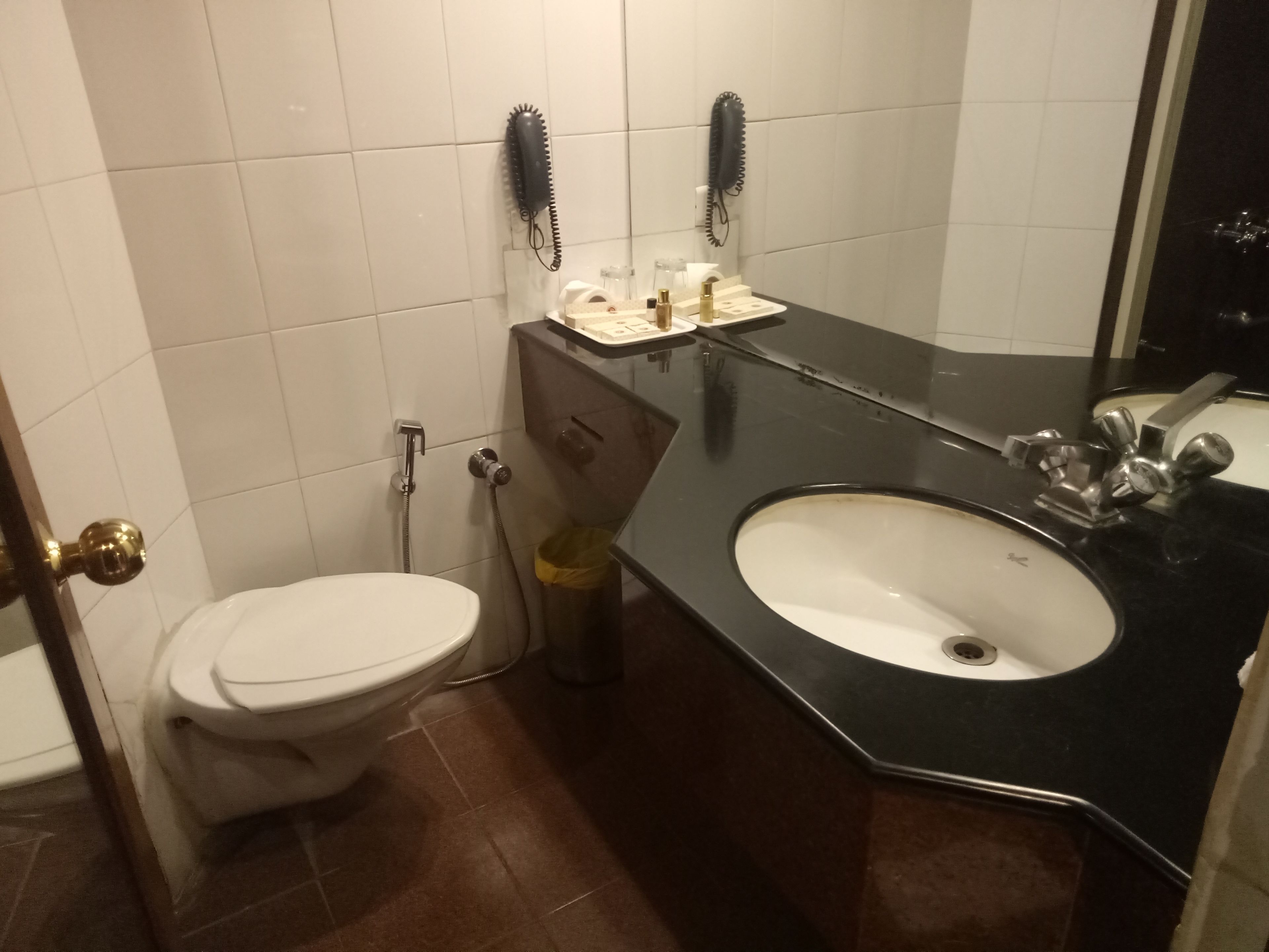 A bathroom with a toilet, sink, and two hair dryers mounted on the wall.