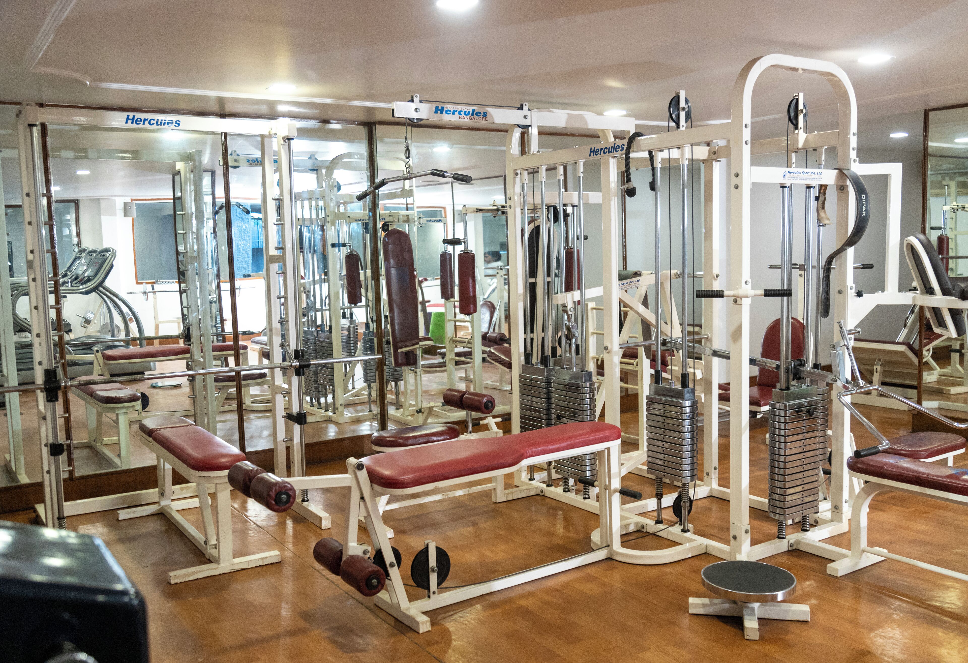 A gym with various exercise machines, benches, and weights.