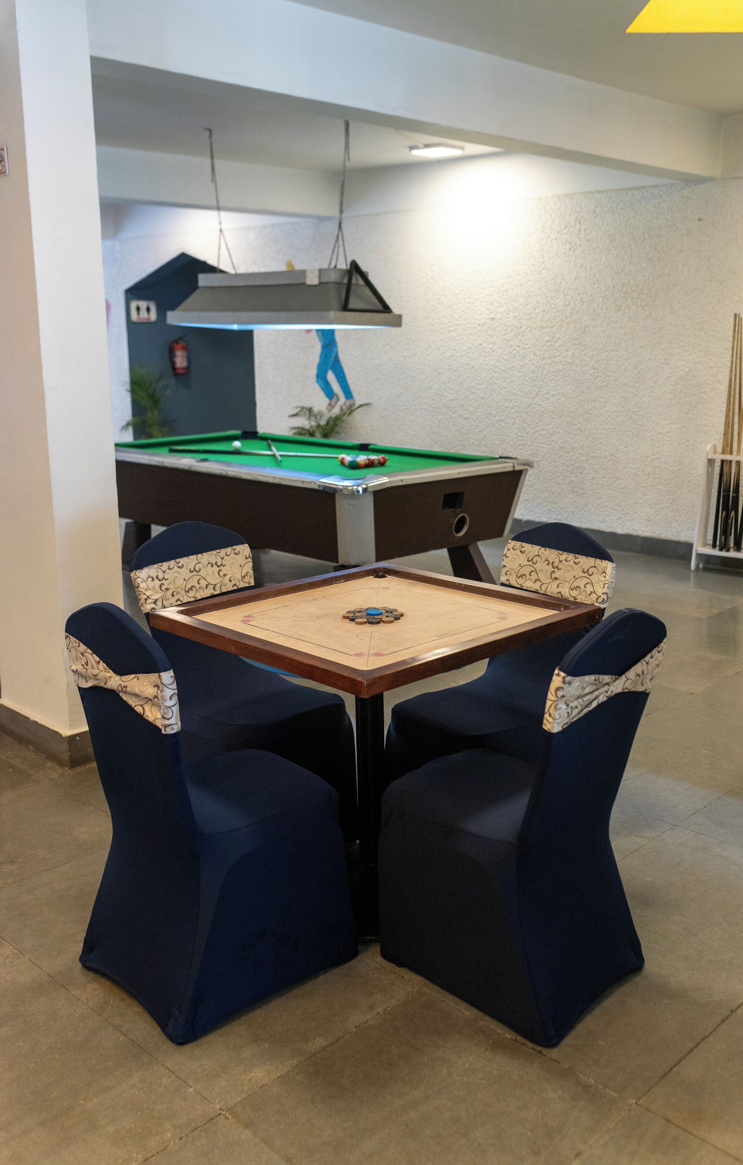 A pool table with four chairs, a pool cue rack, and a pool table in the background.