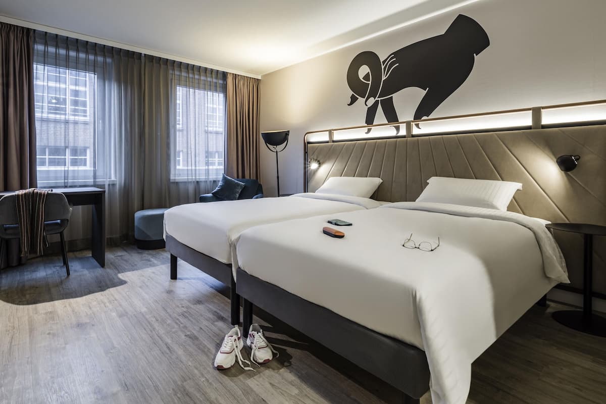 A modern hotel room with a large bed, a desk, and a chair.