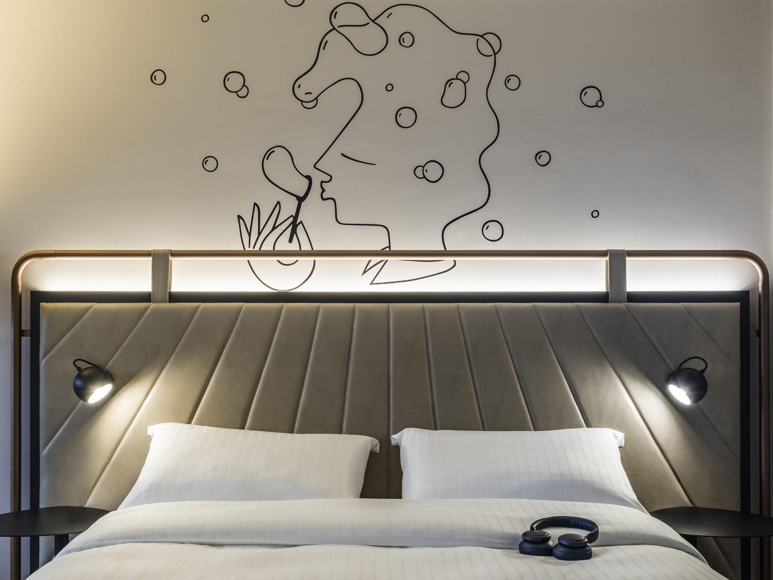 Ein modernes Schlafzimmer mit Kopfteil, zwei Nachttischlampen und einem Wandbild eines Reiters.