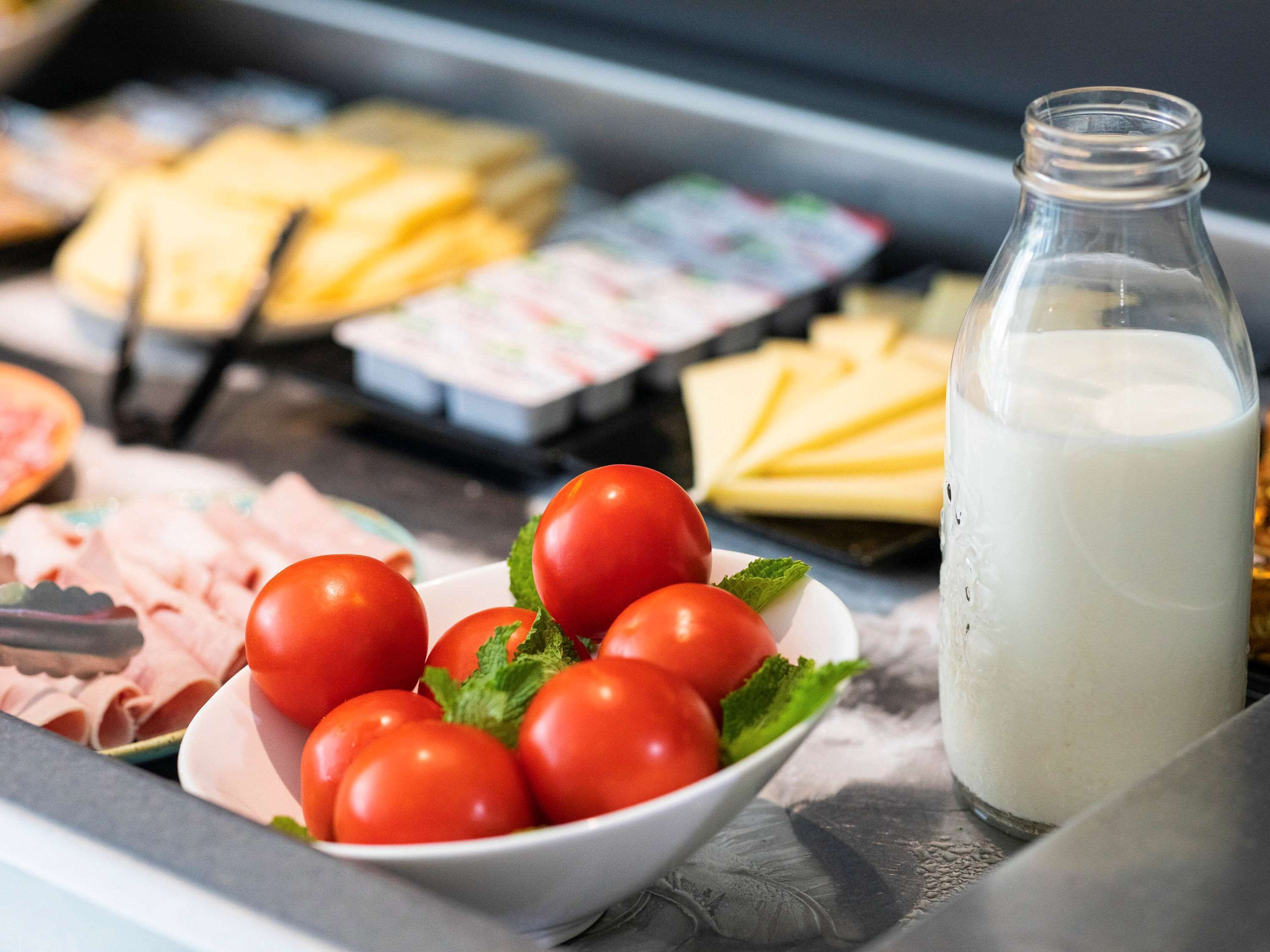 A buffet with various food items including tomatoes, cheese, and milk.