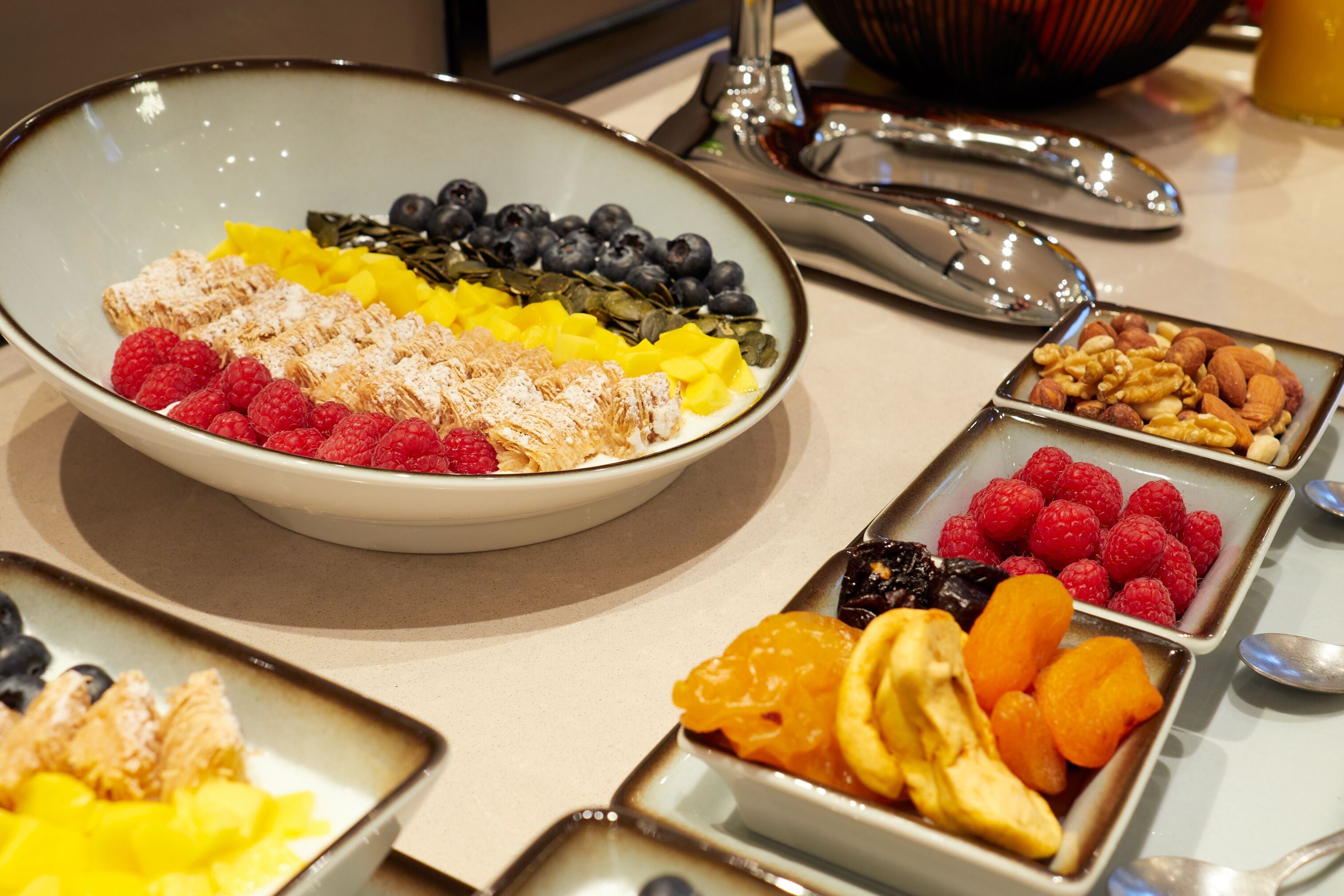 A buffet with various fruits and nuts arranged in bowls and trays.