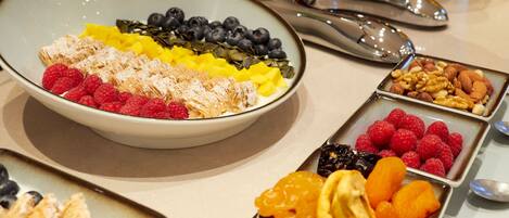 A buffet with various fruits and nuts arranged in bowls and trays.