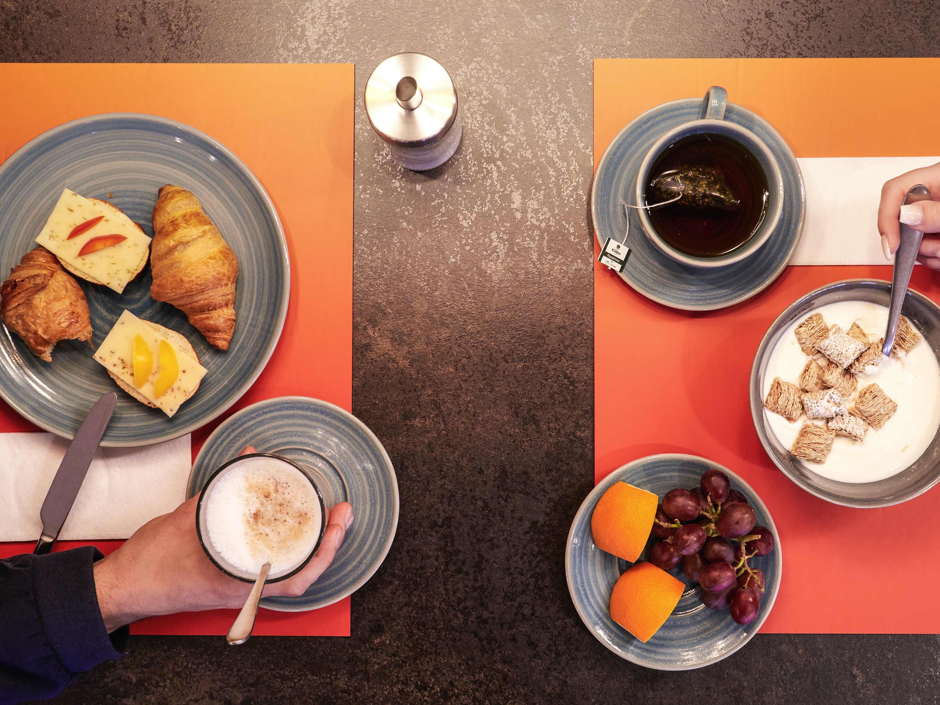 A table with food items including croissants, cheese, fruit, and a bowl of cereal with milk.