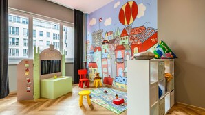 A child's playroom with a cityscape mural, a play table, and a toy storage unit.