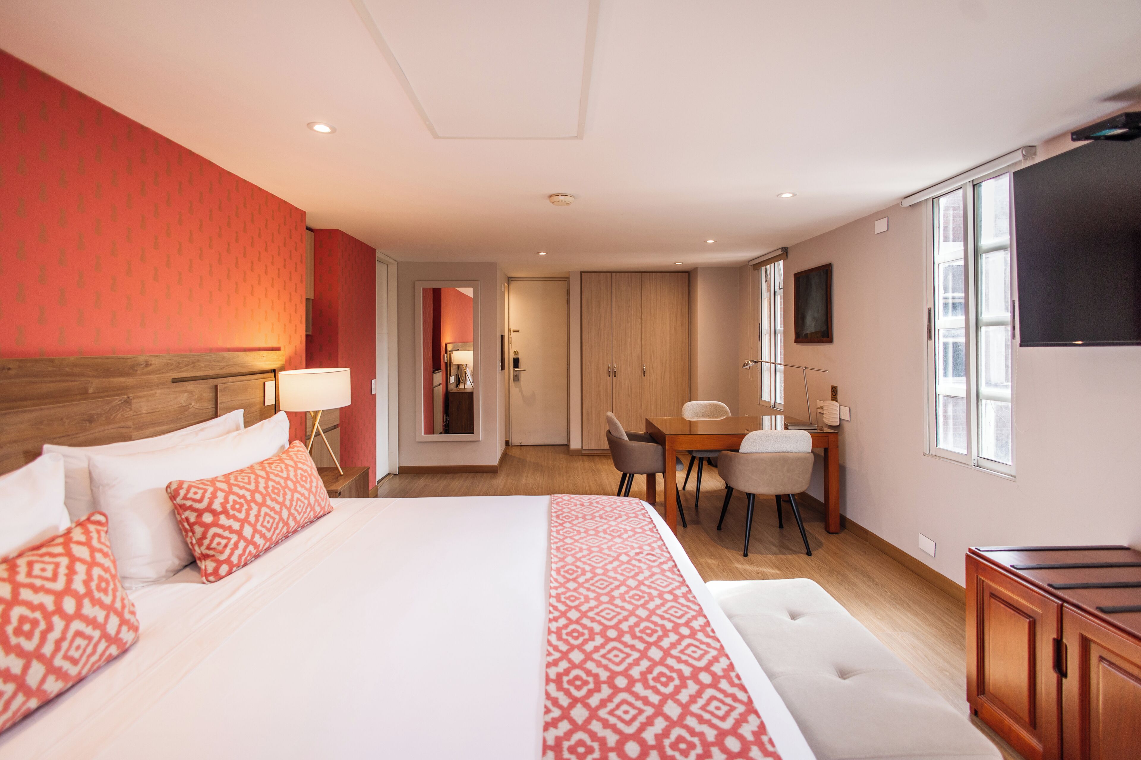 Una habitación de hotel con una cama grande, un escritorio y un televisor.