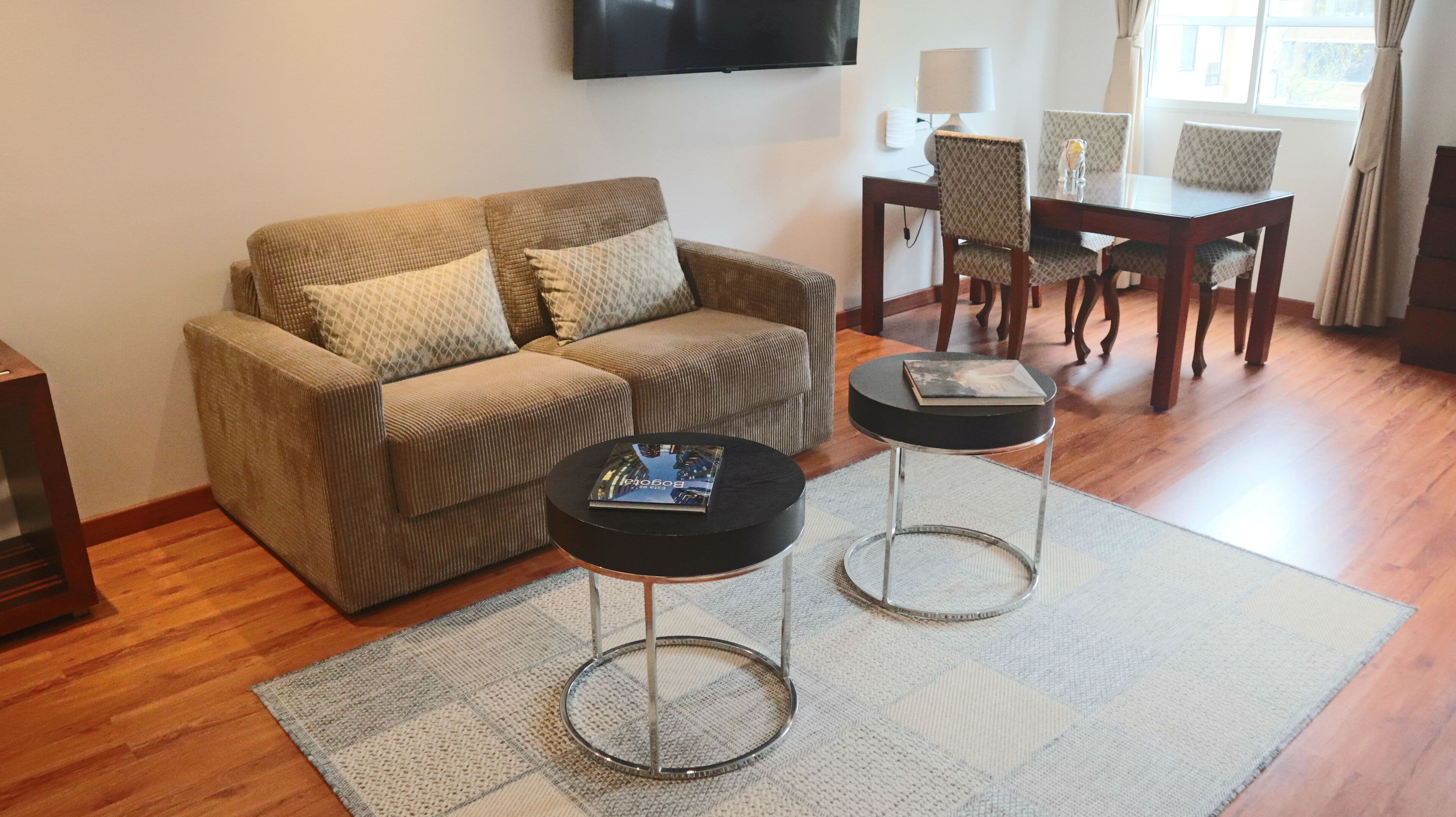 Una sala de estar con un sofá, dos mesas de centro, un televisor y un comedor con sillas y una mesa.