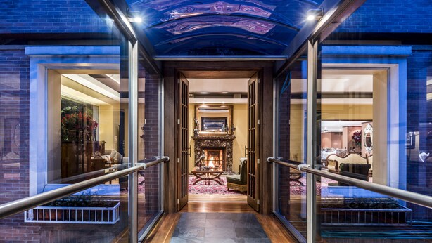 Un hall de hotel con una chimenea central, suelo de madera y barandillas de vidrio a ambos lados.
