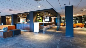 A modern hotel lobby with a reception desk, seating area, and bar. - Postillion Hotel Dordrecht (Dordrecht)