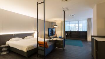 Een moderne hotelkamer met een groot bed, een bureau, een televisie en uitzicht op de stad.