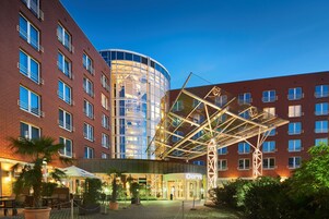 Um hotel com fachada de vidro moderna, área de estar externa e entrada coberta.