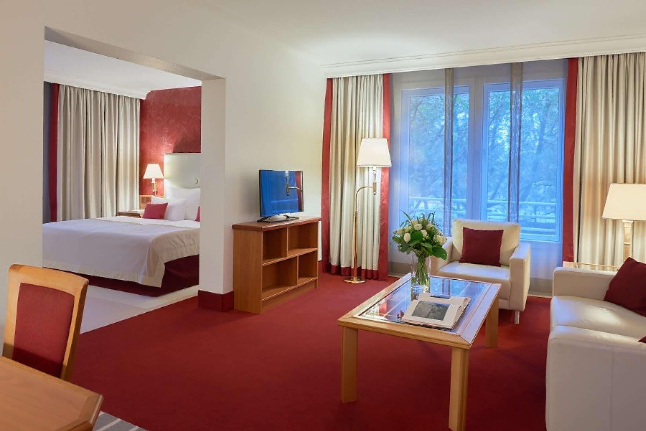 A hotel room with a bed, a desk, a chair, a sofa, and a coffee table.