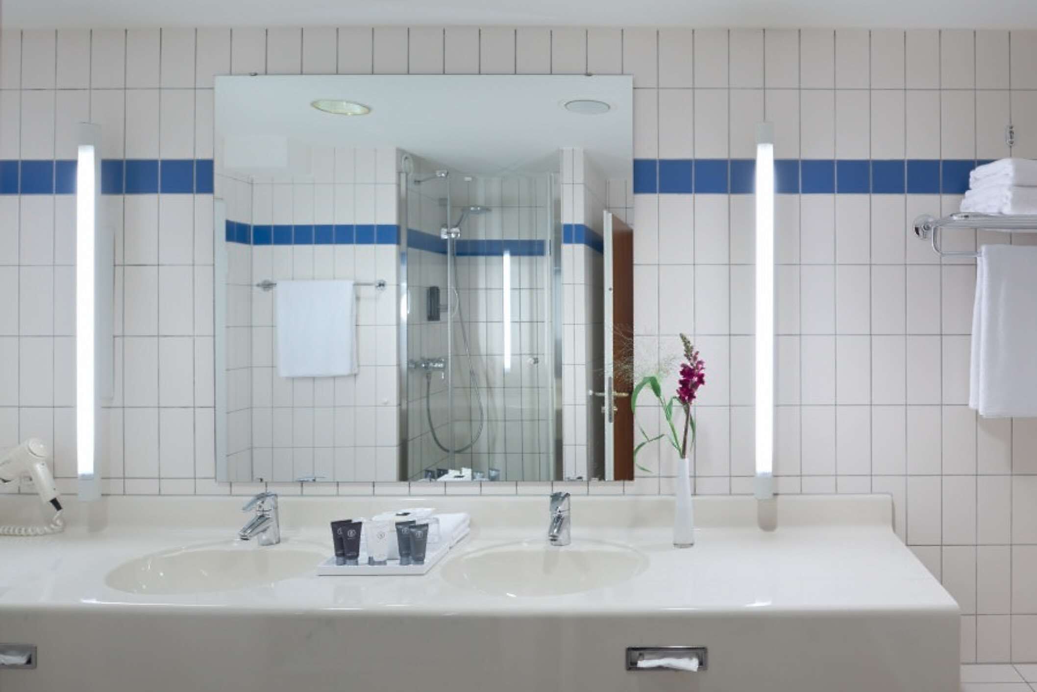 A bathroom with two sinks, a large mirror, and a shower.