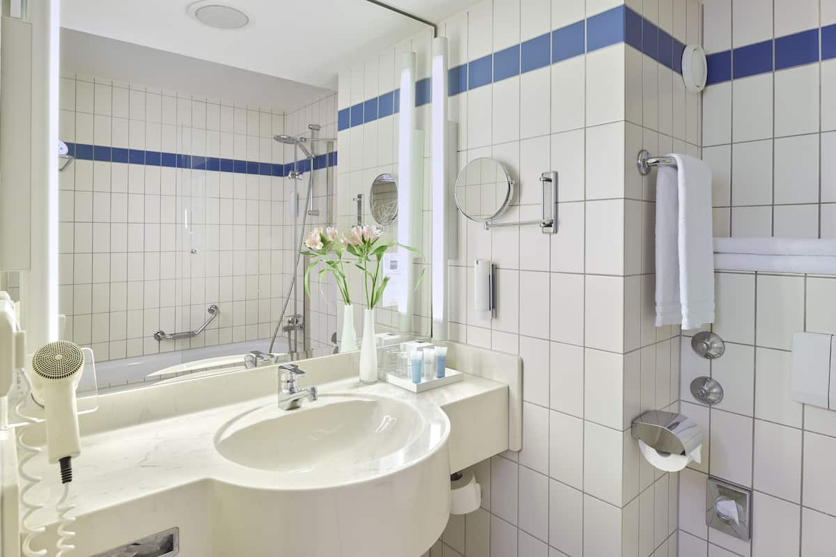 A bathroom with a sink, mirror, towel rack, and shower.