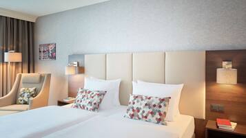 A hotel room with a large bed, two bedside tables, a chair, and a wall-mounted lamp.