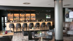 A modern bar area with a wooden counter, black chairs, and a large pillar.