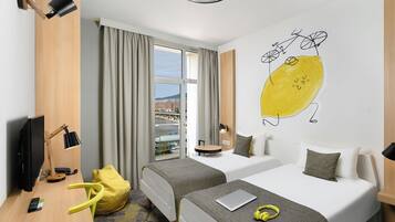 Une chambre d’hôtel avec deux lits, un bureau avec une télévision, une chaise et une fenêtre avec des rideaux.