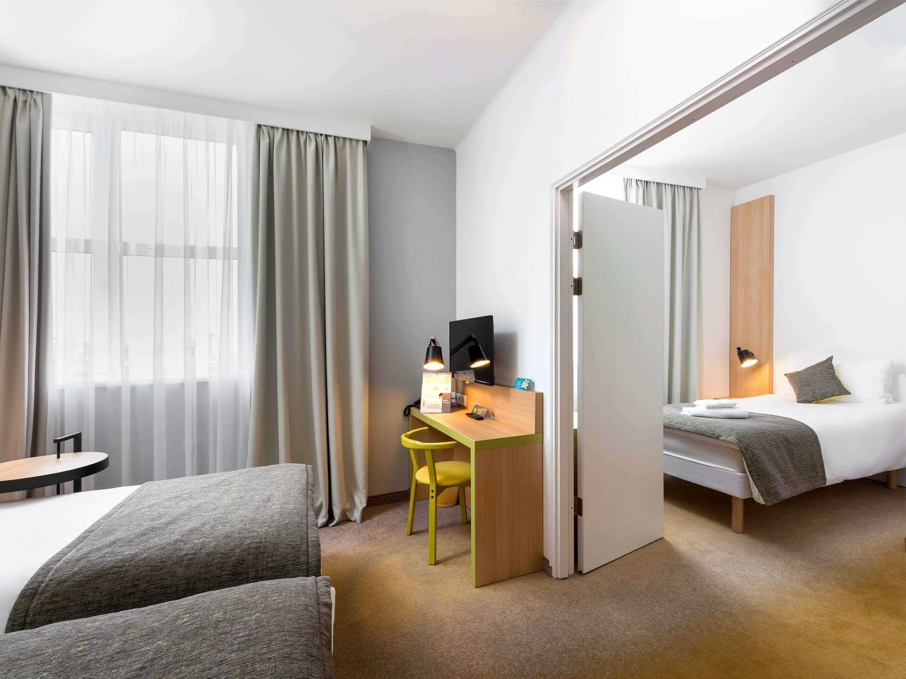 Une chambre d’hôtel avec un lit, un bureau et une chaise, une petite table et un téléviseur.
