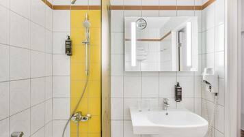 A bathroom with a shower, a sink, a mirror, and a towel rack.