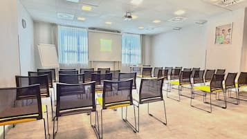 A conference room with rows of chairs, a projector screen, and a whiteboard.