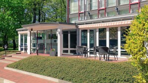 Un edificio moderno con zona de estar al aire libre techada y escaparate de vidrio.