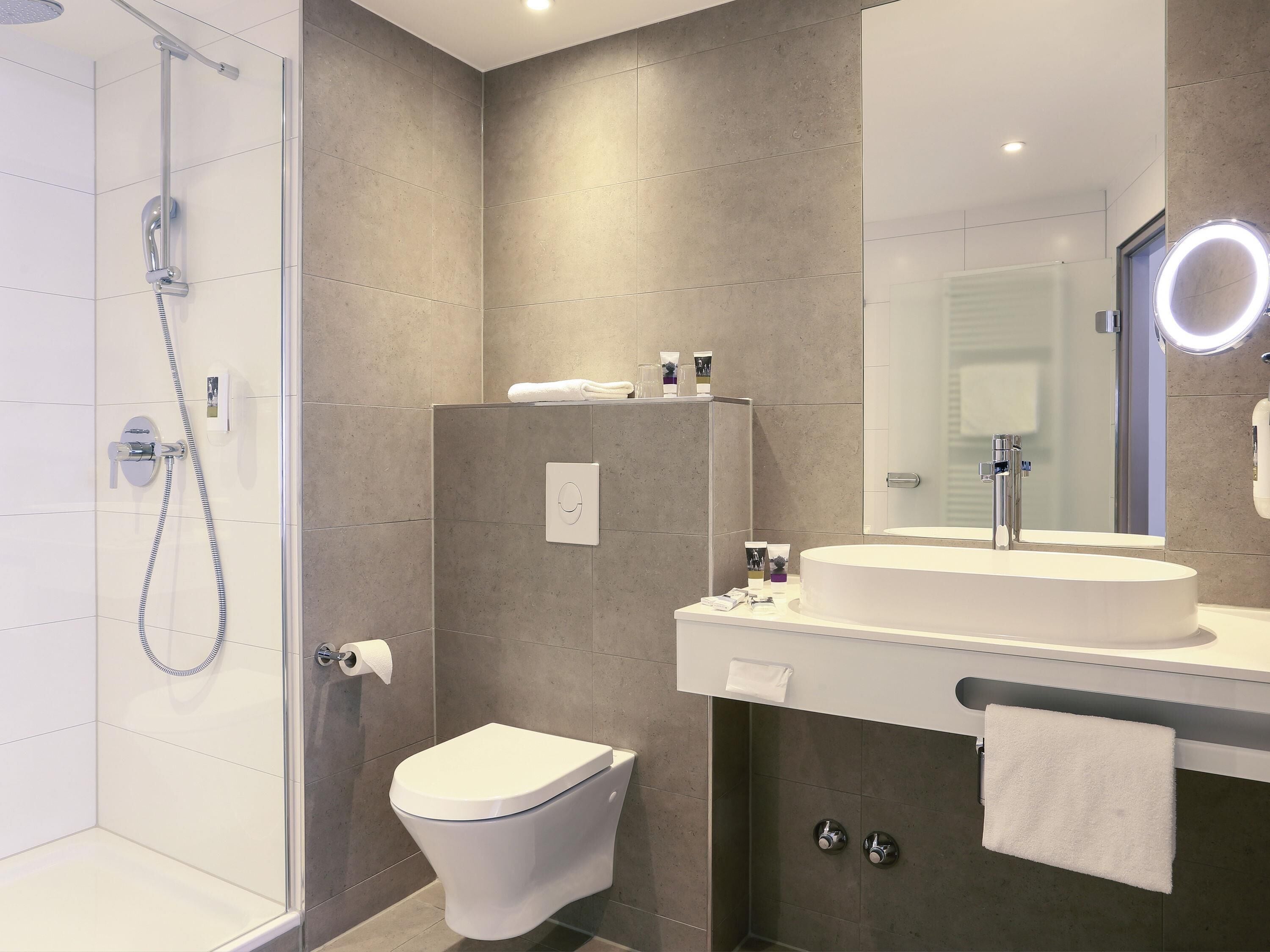 Une salle de bain moderne équipée d’une douche, de toilettes, d’un lavabo et d’un miroir.