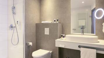 Une salle de bain moderne équipée d’une douche, de toilettes, d’un lavabo et d’un miroir.