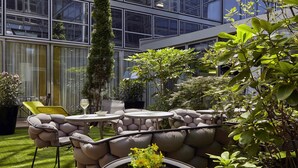 Un espace extérieur moderne, aménagé avec des sièges, un mur en pierre, une pelouse verdoyante et des plantes en pot.