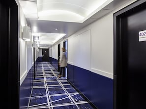 A hotel hallway with a blue and white color scheme, a patterned floor, and a sign indicating room number 402. - Mercure Paris La Défense Grande Arche (Nanterre)