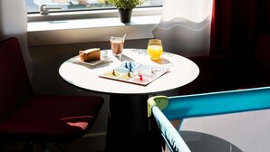 Una mesa con una rebanada de pastel, un vaso de leche, un vaso de jugo de naranja y una pequeña planta en maceta.