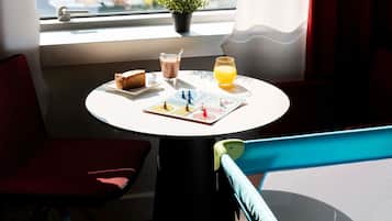Een tafel met een stukje taart, een glas melk, een glas jus d'orange en een kleine plant in een pot.